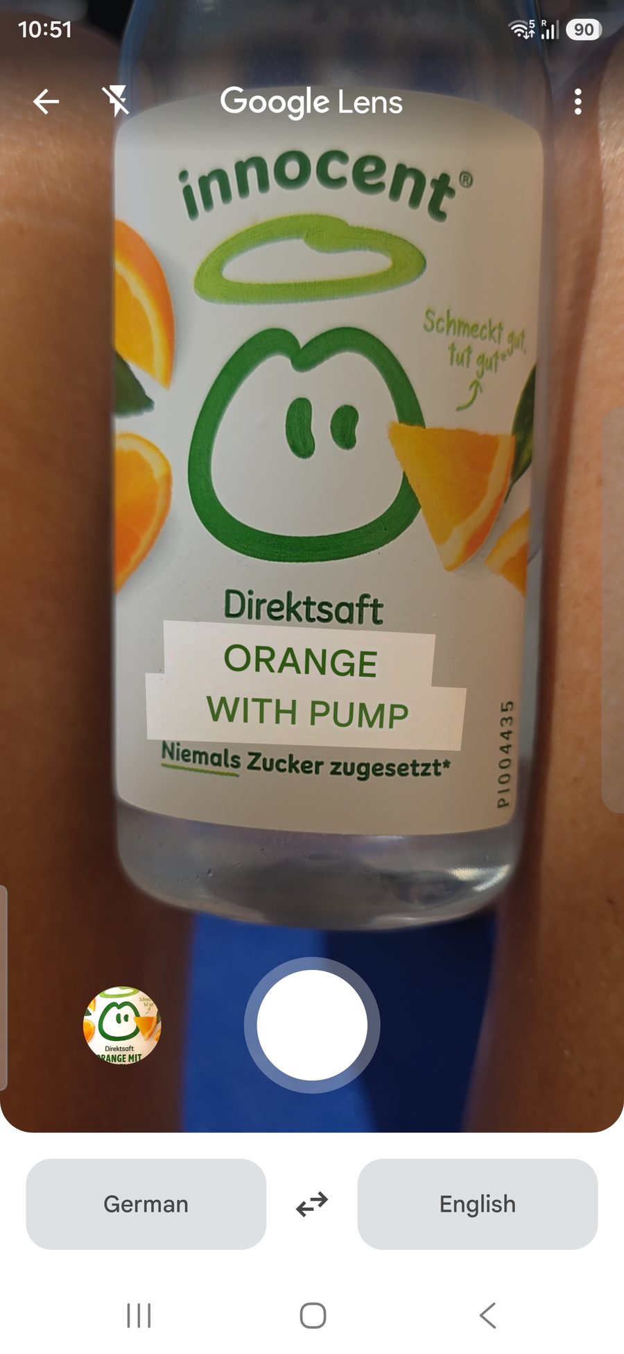 A bottle of innocent Direktsaft seen through Google Lens. The live translation overlay has replaced the German variety name with the English words ORANGE WITH PUMP.